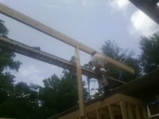 Carpenter setting a ridge beam over a new addition frame — Ice Dam Removal by Roofing Brothers in Creedmoor