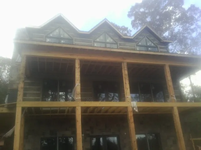Dormers and porch framing on a large log home under construction — Roof Coating work by our crew in Creedmoor