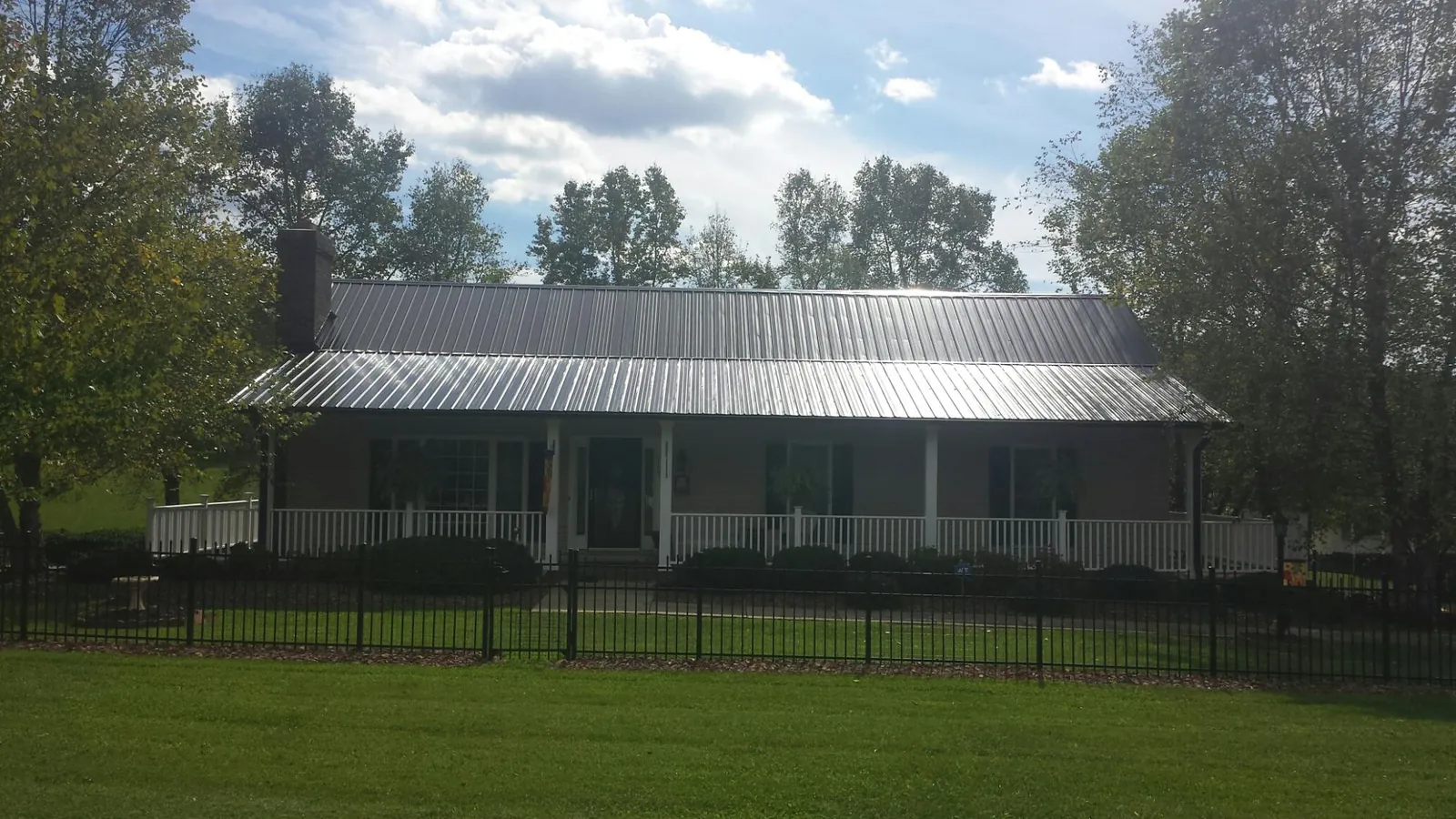 Gray metal roof on a brick ranch with a full width front porch — Gutter Guard Installation work by our crew in Creedmoor